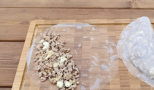 1. Этап. Чебуреки из индейки в рисовой бумаге: Рисовую бумагу опустить в чуть теплую воду на 30 секунд. Положить на доску, выложить 1 порцию фарша на одну сторону чебурека и накрыть другой. Края закрепить нажатием пальцев.