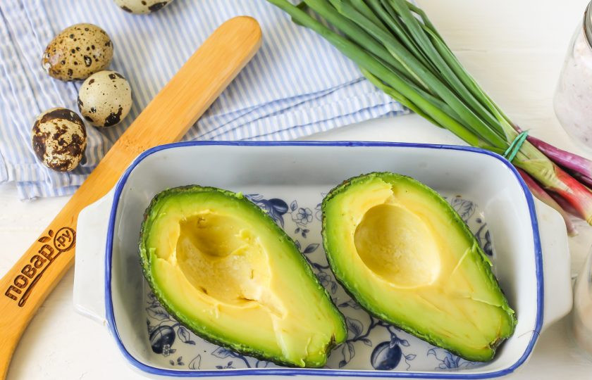 1. Этап. Яйца на завтрак: Выберите качественный плод авокадо со слегка мягковатой текстурой. При нажатии плод не должен пружинить, а должен слегка продавливаться. При этом на кожуре не должно быть темных пятен. Разрежьте его вертикально пополам и прокрутите половины в руках, они легко отделятся друг от друга. Чайной ложкой удалите косточку, не повреждая мякоть авокадо. Выложите обе половинку в форму для запекания.