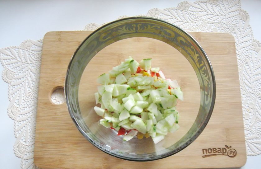 1. Этап. Зеленый салат с крабовыми палочками: Огурец помойте, очистите и мелко нарежьте. Добавьте в салат.