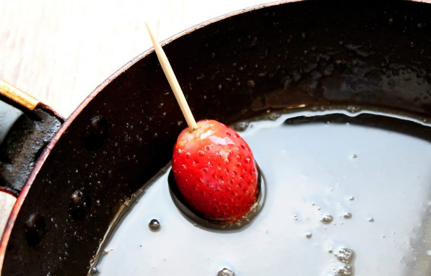 1. Этап. Карамелизированная клубника: Опустите каждую ягодку в карамель, чтобы она полностью покрылась. Поднимите и дайте стечь лишней карамели.