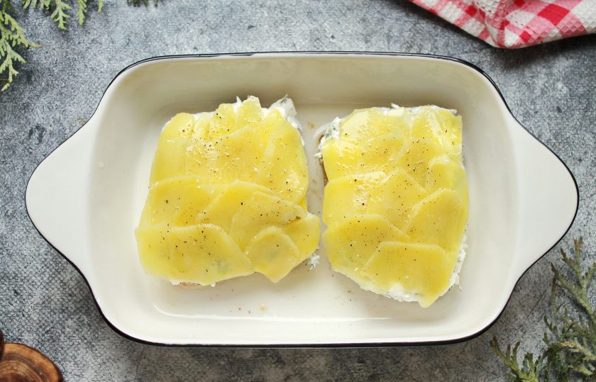 1. Этап. Треска по-поморски: Выложите слайсы картофеля внахлест на творожный слой. Смажьте картошку растопленным сливочным маслом, поперчите.