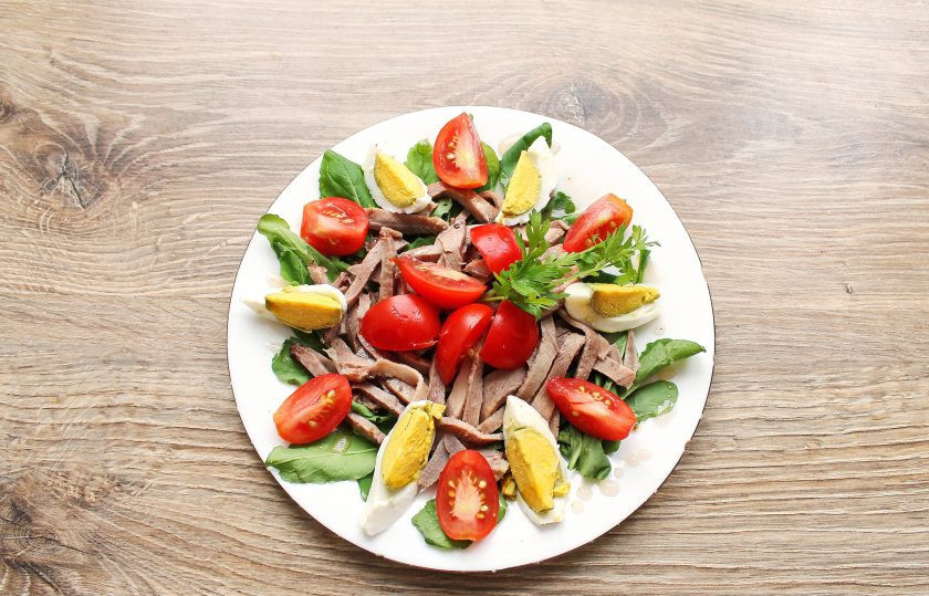 1. Этап. Салат с рукколой и языком: Помидорки черри разрежьте дольками и выложите на салат. Украсьте петрушкой и подавайте к столу.