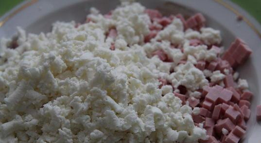 1. Этап. Пирожки с колбасой: Теперь готовим начинку. Колбасу режем мелкими кубиками и смешиваем с сыром, натертом на терке.