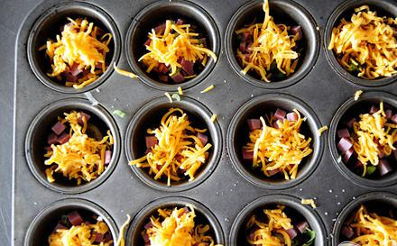 1. Этап. Картофель с сыром и зеленым луком: 3. Затем положить в каждое отделение ломтик картофеля, щепотку соли и перца, затем тертый сыр Чеддер и нарезанный зеленый лук. Повторить слои: картофель, соль и перец, сыр, лук. Сделайте таким образом 2-3 слоя. При желании можно добавить слой нарезанной кубиками ветчины.