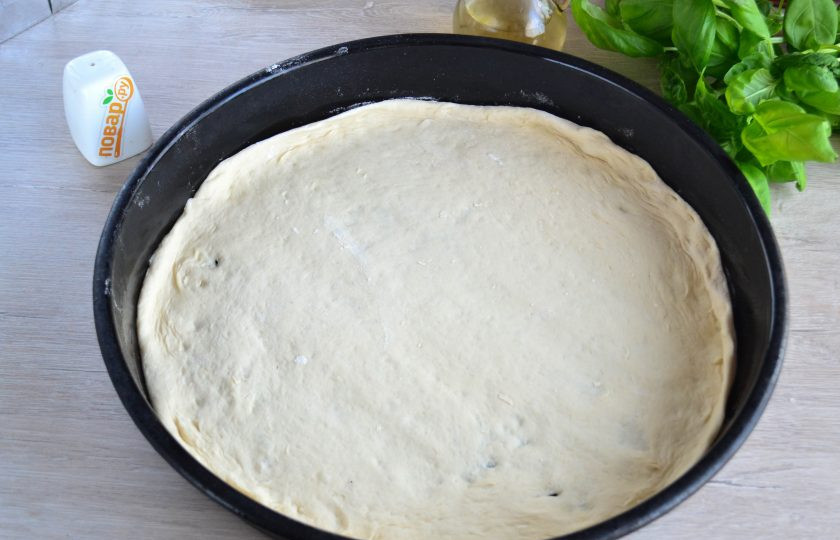 1. Этап. Пицца Каприччиозо: Тесто поднялось. Указанного количества теста хватает на две пиццы диаметром 30 см. Духовку предварительно включите разогреваться до температуры 200-250 градусов, сколько позволяет ваша духовка. Противень смажьте растительным маслом. Тесто разделите пополам, одну часть тонко раскатайте, выложите в противень и сформируйте бортики.