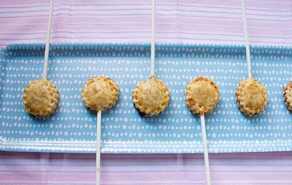 1. Этап. Мини-пирожки на палочке: 5. Слегка взбить яичный белок в небольшой миске и смазать им пирожки. Затем посыпать сахаром. Выпекать первые 2 противня примерно 14-16 минут до слегка золотистого цвета, поменяв противни местами в середине времени приготовления. Выпекать оставшийся противень с пирожками 14-16 минут.