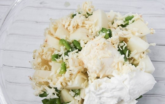 1. Этап. Картошка со свининой в духовке: Сперва очистите и нарежьте картофель кусочками, смешайте его с тертым сыром, сметаной, майонезом, измельченный болгарским перцем и чесноком.