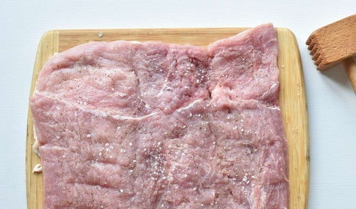 1. Этап. Рулет из свинины с цветной капустой: Пока капуста тушится, подготавливаю мясо к фаршированию. Для этого накрываю его полиэтиленовой пленкой, для избежания разбрызгивания, и отбиваю в пласт. Посыпаю мясо солью и молотым черным перцем.