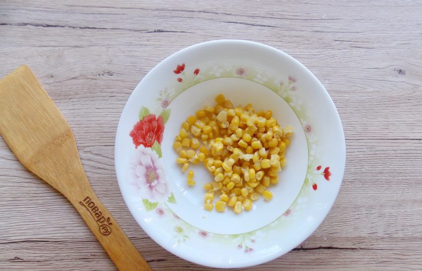1. Этап. Салат Желтый одуванчик с кукурузой: Из банки с консервированной кукурузой слейте рассол и кукурузу выложите в миску.