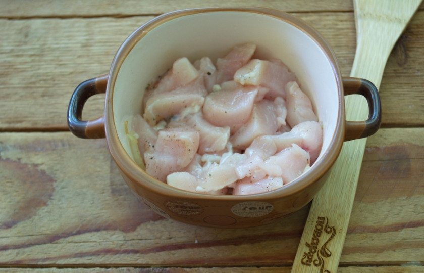 1. Этап. Грудка с помидорами и сыром: Обжаренный лук выкладываем в смазанный маслом горшочек или такую кастрюльку как моя. Поверх лука выкладываем нарезанное мясо птицы. В качестве мяса можно использовать не только филе, но и мясо с ноги. Главное без костей. Мясо нужно посолить и поперчить.