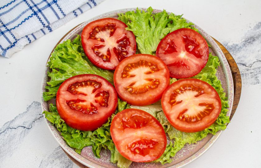 1. Этап. Помидоры с творожным сыром и чесноком: Блюдо выстелите листьями салата. Помидоры промойте и просушите. Нарежьте кружочками и переложите на блюдо.