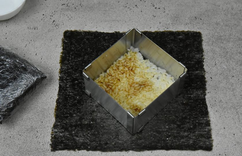 1. Этап. Суши сэндвич с креветкой: Готовый рис разделите на четыре части, примерно по 115-120 граммов. Выложите в форму половину одной части риса 57-60 граммов. Сверху нанесите на рис 1 ст.л. соуса терияки и и распределите по всей поверхности рисового слоя. Сверху можно нанести тонкий слой творожного сливочного сыра. Можете использовать соус и сыр одновременно или по отдельности.