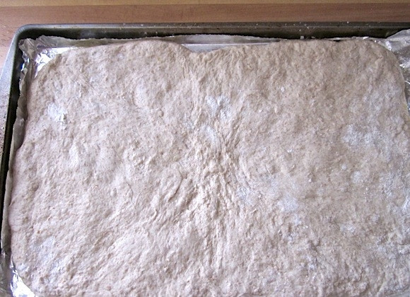 1. Этап. Фокачча (без вымешивания теста): 5. Посыпьте противень кукурузной мукой, затем выложите тесто и разровняйте его руками по всей поверхности.