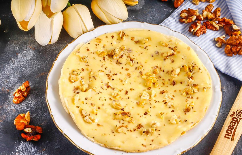 1. Этап. Торт Наполеон с грецкими орехами: Выложите первый корж на тарелку, обмажьте остывшим кремом и присыпьте измельченными ядрами грецких орехов. Их можно заранее слегка обжарить на сухой сковороде.