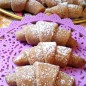 Цельнозерновые песочные рогалики Тесто я замешиваю с помощью комбайна, насадкой крюк. В чашу комбайна наливаем растопленный смалец или растительное масло. В оригинале рецепта было растительное масло. Я же делаю на смальце, так как именно он даёт большую рассыпчастость. Также вливаем сильно газированную воду. Добавляем муку, смешанную с содой. Тесто должно собраться в шар и быть мягким. Завернуть в пищевую плёнку и на полчаса в холод. Тесто я разделяю на части. Каждую часть раскатываю в тонкий пласт, присыпаю чуть сахаром, прокатываю ещё раз скалкой, чтобы вдавить сахар в тесто. Разрезаю на сегменты и заворачиваю рогалики ( от внешней стороны к середине). Выкладываю на противень с пергаментом и выпекаю в разогретой духовке при 180 градусах до золотистого цвета, примерно 15-20 минут У меня получилось два таких противня рогаликов. Испеченные рогалики я выложила на стол остывать, а сама тем временем занялась приготовлением сиропа. Мёд с водой доводим до кипения. По одному или по парочке рогаликов, провариваем с обоих сторон в сиропе 1-2 минуты. Выкладываю на поднос и сразу посыпаю сахарной пудрой. Красиво, сытно и вкусно. Рогалики рассыпчастые и ломкие, не дубовые. Приятного чаепития!