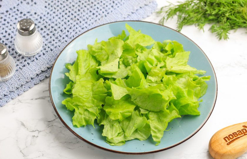 1. Этап. Салат из масляной рыбы холодного копчения: Промойте листья салата в воде и стряхните лишнюю влагу. Срежьте стебли и нарвите зелень руками на тарелку.