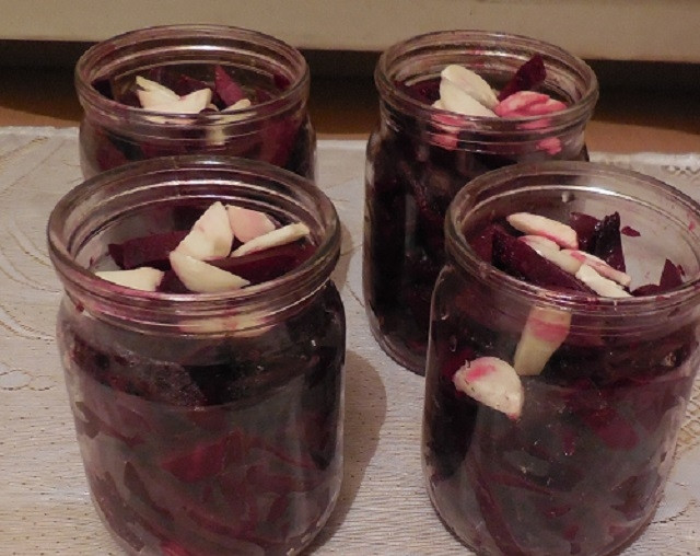 1. Этап. Салат со свеклой на зиму: Разложите свеклу по чистым баночкам, сверху уложите чеснок. Сварите маринад. Воду с маслом, сахаром и солью доведите до кипения.