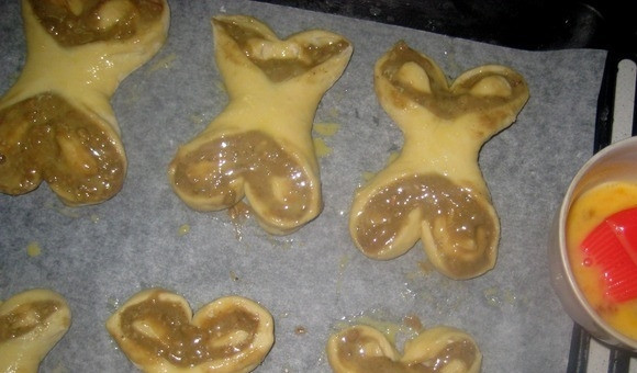 1. Этап. Булочки облитые халвой: Выложите изделия на противень с пергаментом. Оставьте их на 15 минут. Смажьте их взбитым яйцом, а также остатками начинки.