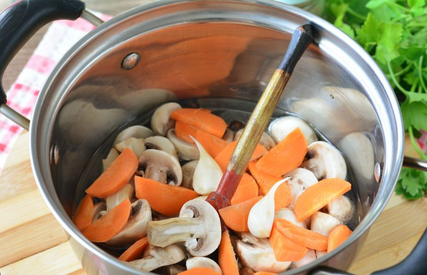 1. Этап. Маринованные грибы с морковью: Всыпьте к грибам нарезанную полукольцами морковку и зубчики чеснока. Варите все вместе 5-7 минут.