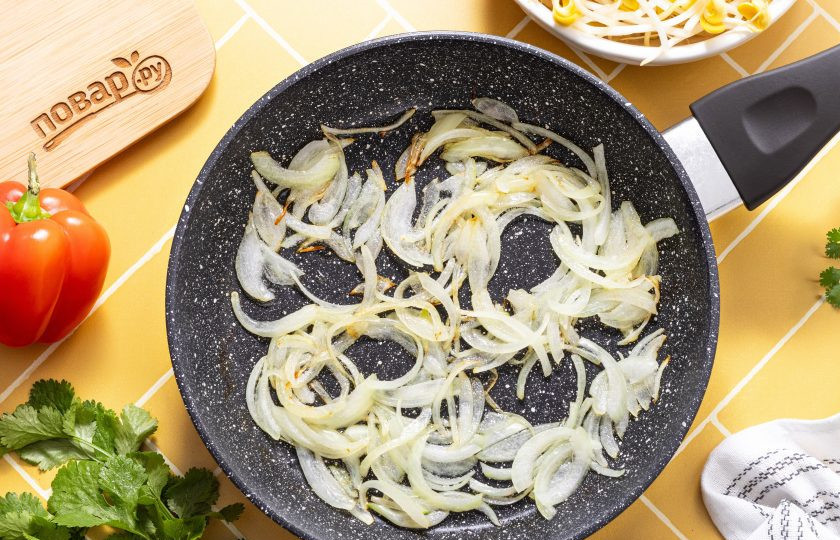 1. Этап. Салат из пророщенной сои по-корейски: Разогрейте сковороду на среднем огне и обжарьте репчатый лук до румяного цвета.