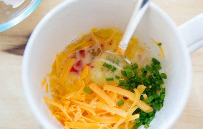 1. Этап. Омлет в микроволновке за 5 минут: 3. Нарежьте мелко перец и зеленый лук, натрите на терке сыр. Выложите все ингредиенты в чашку.