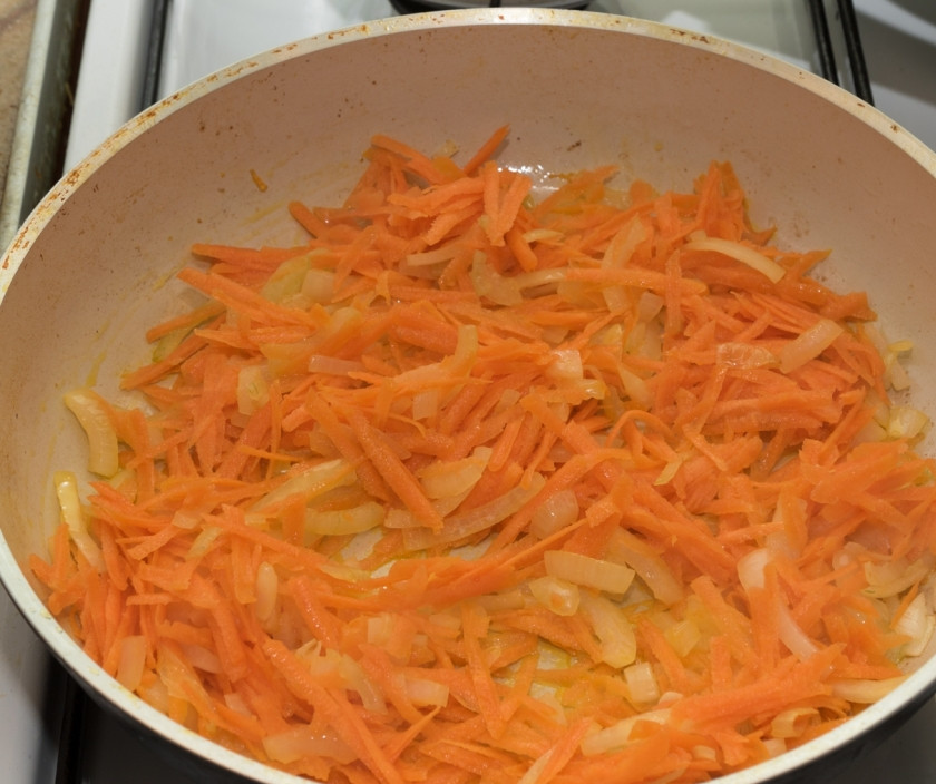 1. Этап. Жареные кальмары с овощами: Нарежем лук четвертькольцами, натрем морковь на крупной терке, отправим на сковороду тушиться в небольшом количестве масла.