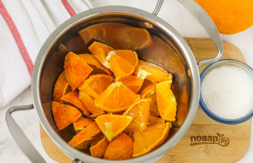 1. Этап. Компот из апельсина и лимона: Ошпарьте цитрусовые кипятком и снимите цедру с апельсина — она может горчить. Используйте ее в других рецептах. Затем разрежьте плод на четыре части и удалите косточки, если они там присутствуют. Нарежьте ломтиками и выложите нарезку в кастрюлю.