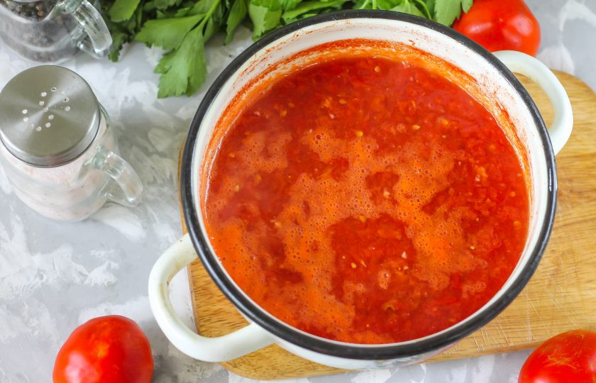 1. Этап. Приправа из помидоров на зиму: Поместите кастрюлю на плиту и доведите томатную массу до кипения, затем уменьшите нагрев до минимального или среднего, протомите содержимое емкости около 20 минут. По желанию, можно уварить и дольше, если хотите получить густую массу. Спустя указанное время влейте в емкость растительное масло и уксус, доведите еще раз массу до кипения.