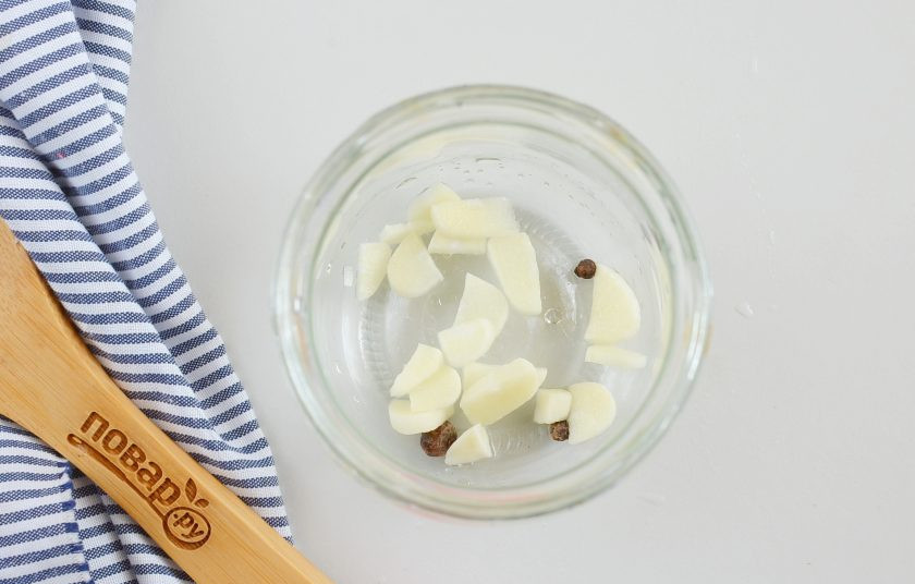 1. Этап. Огурцы в томатном соусе: На дно каждой банки выложите по 2 горошины чёрного перца, по 1 горошине душистого перца и по 2 зубчика очищенного и нарезанного крупно чеснока.