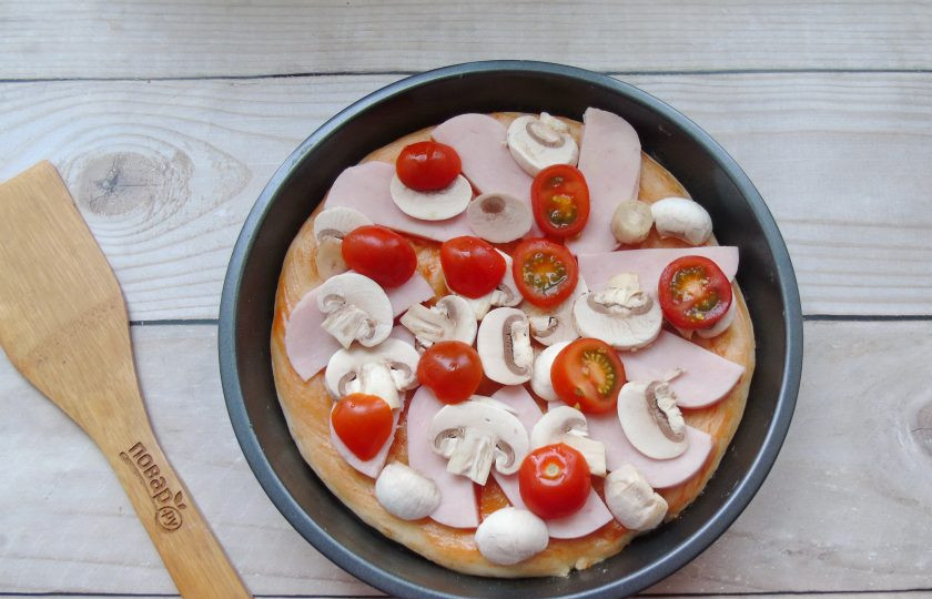 1. Этап. Пицца с ветчиной и грибами: Помидоры черри нарежьте разложите на пиццу. Их можно заменить обычными помидорами. Отправьте пирог в духовку, разогретую до 185-190 градусов. Пеките 25-30 минут. Время выпекания зависит от вашей духовки.