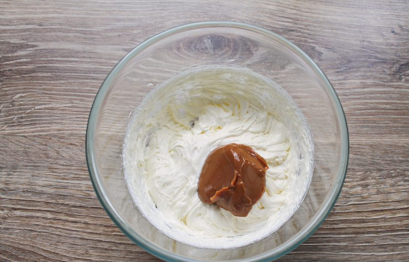 1. Этап. Торт Вриндаван: Прибавьте скорость, продолжая взбивать, добавляйте по столовой ложки вареное сгущенное молоко.