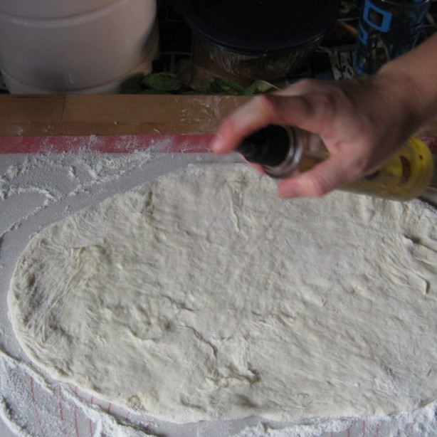 1. Этап. Пицца по-домашнему: Сбрызгиваем раскатанное тесто оливковым маслом.