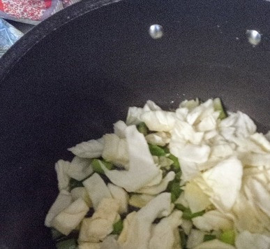 1. Этап. Лапша с арахисовым маслом и кочуджаном: К зелёному луку добавить мелко нашинкованную капусту. Готовить, постоянно помешивая 8 минут.