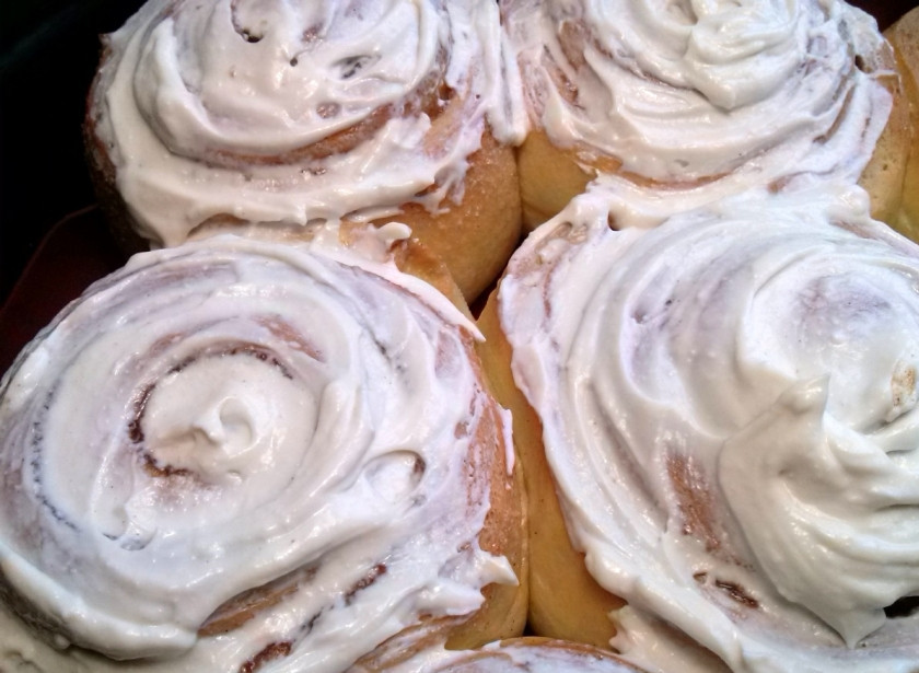 1. Этап. Булочки с корицей Синнабон: Пока булочки выпекаются, приготовьте крем. Смешайте сливочный сыр с размягченным маслом, сахарной пудрой и ванилином. Готовые булочки не вынимайте из формы. Дайте им остыть около 5 минут, а потом нанесите крем.