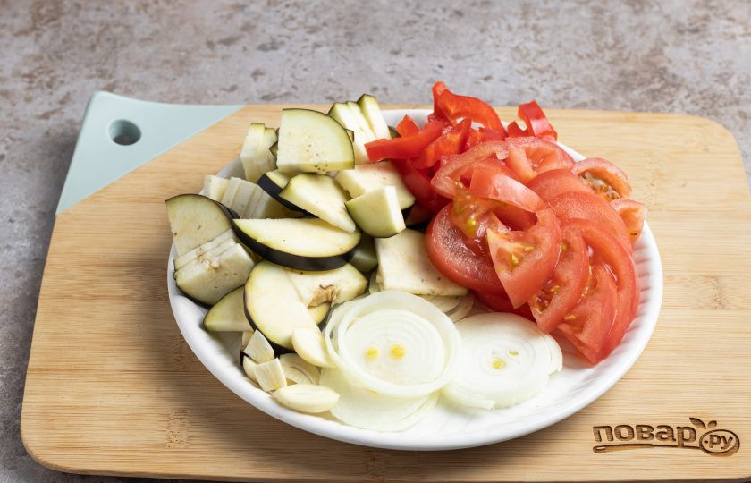 1. Этап. Соус Демиглас из овощей: Баклажан, лук и помидоры порежьте кружочками, зубчики чеснока разрежьте вдоль, а болгарский перец очистите от семян и нарежьте ломтиками.