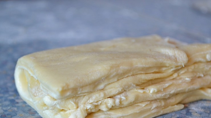 1. Этап. Плацинды с творогом: Разрежьте тесто вдоль скалки. Снимите сверху прямоугольник. Разделите его на 2 квадрата. Уложите один на другой и сложите пополам. Тоже самое проделайте с остальной массой, создавая слоёное тесто. Оставьте его в холодильнике на 3 часа.