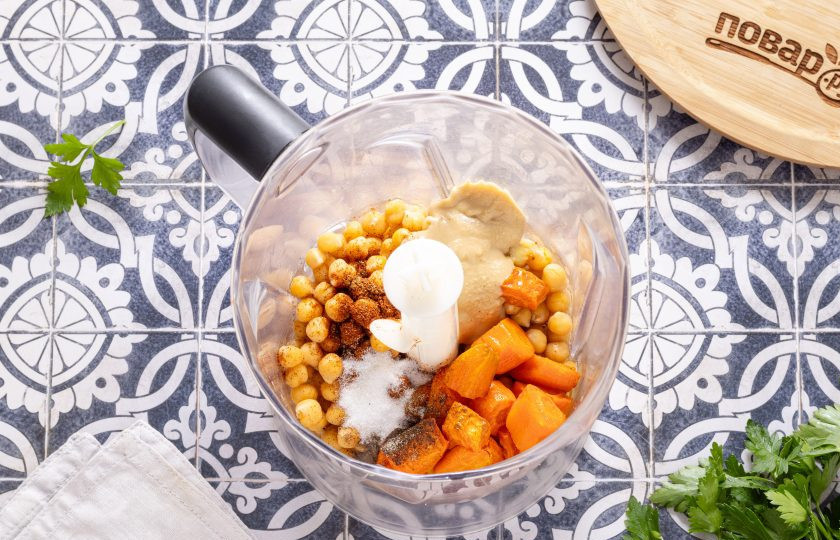 1. Этап. Хумус «Марокканский»: Переложите в чашу блендера вареный нут, морковь, выдавите из кожуры зубчики запеченного чеснока. Добавьте соль, все специи, кунжутную пасту, масло, в котором запекали морковь и воду (примерно 100 мл.), в которой варился нут. Измельчите до однородной консистенции.