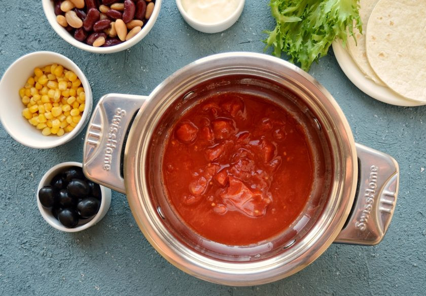 1. Этап. Тако с фасолью: В кастрюлю с толстым дном вылейте измельчённые томаты. На среднем огне уварите их, чтобы лишняя жидкость испарилась.