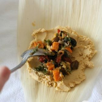 1. Этап. Вегетарианское тамале: 6. Взять один из пропитанных водой кукурузных листьев и намазать толстым слоем мучной массы сверху. Ложкой выложить начинку в центр.