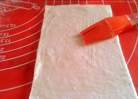 1. Этап. Булочки с корицей без дрожжей: Разогрейте духовку до 180 градусов. Присыпьте рабочую поверхность мукой. Раскатайте тесто скалкой в одном направлении. Сильно не раскатывайте. Каждый лист разрежьте на две части и смажьте растопленным сливочным маслом.