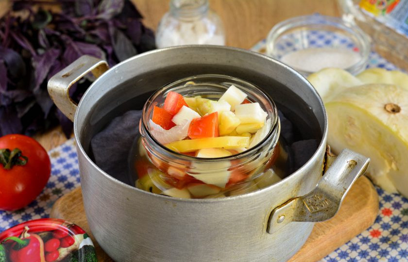 1. Этап. Салат из патиссонов на зиму: На дно кастрюли выстелите кусочек ткани, налейте воду и немного подогрейте. Установите банку с салатом в воду и дождитесь, когда жидкость в кастрюле закипит. Стерилизуйте салат 15 минут.