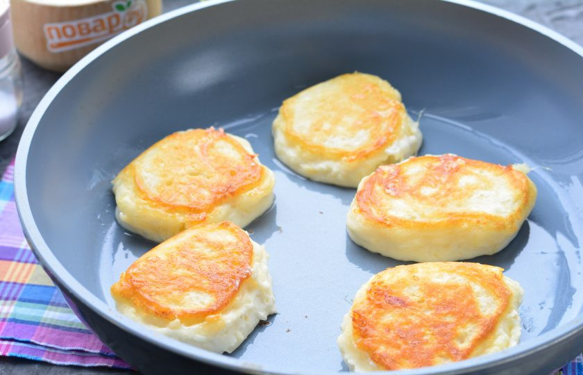 1. Этап. Оладьи с сыром на кефире: Смажьте сковороду маслом, ложкой выкладывайте оладьи. Обжаривайте с двух сторон на среднем огне по 2-3 минутки до румяной корочки.