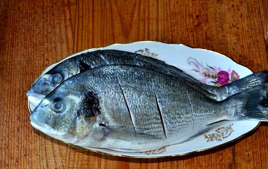 1. Этап. Дорадо на мангале: Рыбку промойте, очистите от чешуи и внутренностей. Острым ножом сделайте косые надрезы с двух сторон тушки.