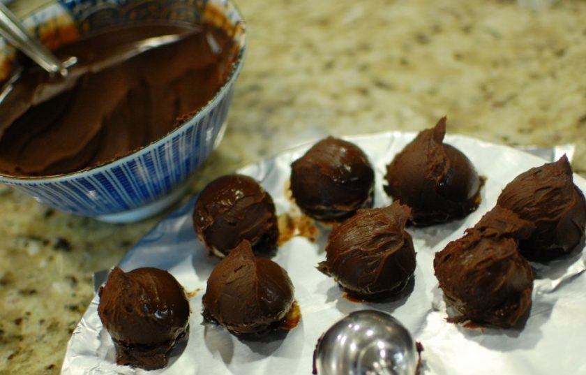 1. Этап. Домашний трюфель: 6. Накройте каждую тарелку пленкой и отправьте смесь на 3 часа в холодильник. Спустя необходимое время достаньте и ложкой возьмите немного шоколадной массы. Вручную или с помощью специальной ложки придайте массе форму шариков. Выложите все шарики на поднос и отправьте в морозильную камеру на 20 минут.