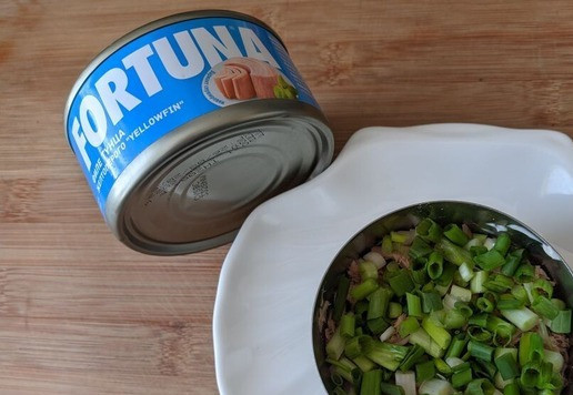 1. Этап. Салат Кудрявый Ваня: Зелёный лук чистим, режем колечками, половину зелёной части оставляем на украшение. Кладём лук на слой тунца. Смазываем майонезом.