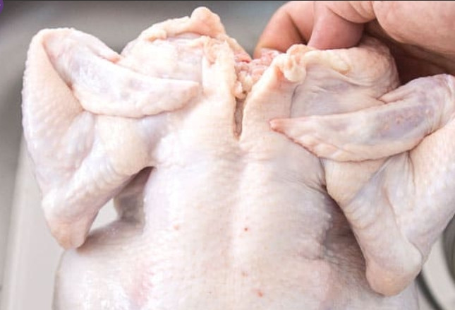 1. Этап. Запеченная курица с хрустящей корочкой: 2. Промойте и тщательно промокните от воды курицу. Загните ей крылышки в обратную сторону.