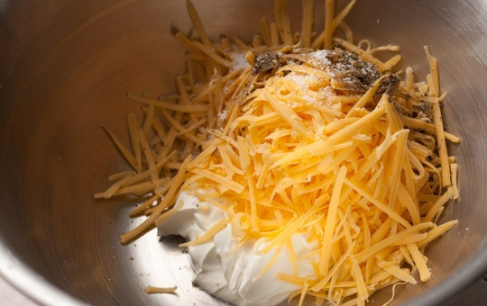 1. Этап. Подлива к картофельной запеканке: 2. Тем временем в отдельную миску натрите на крупной терке сыр, выложите сметану, соль и черный молотый перец, перемешайте.