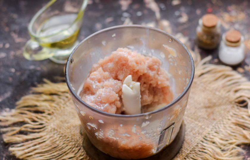 1. Этап. Перцы фаршированные куриной грудкой в духовке: Куриную грудку сполосните и нарежьте средними кусочками, измельчите в чаше блендера, добавьте сливки и измельчите повторно.