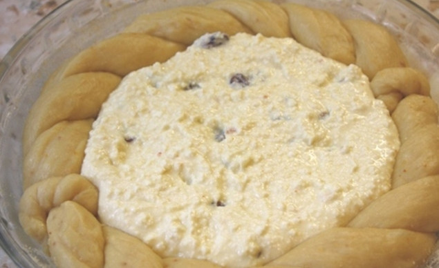 1. Этап. Румынский козунак с творогом: Когда тесто увеличится в два раза, разделите его на две части. Из первой раскатайте круг и выложите его в форму для запекания. Затем из второй части сделайте плетенку и выложите ее так, чтобы получился бортик. В углубление выложите начинку.