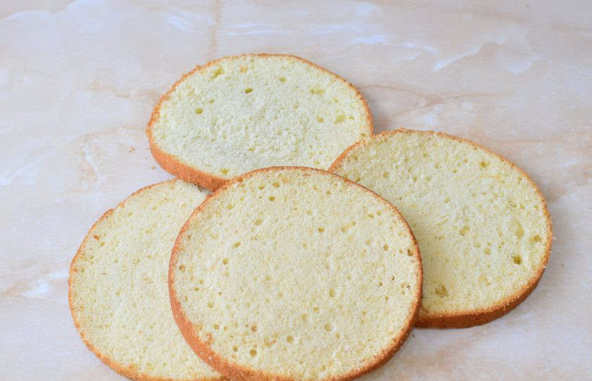 1. Этап. Торт с консервированными персиками и взбитыми сливками: Готовый бисквит немного увеличится в размере, подрумянится и будет пружинить при надавливании. Извлеките его из духовки и остудите. Затем оберните пищевой пленкой и уберите на ночь в холодильник. Перед сборкой торта разрежьте бисквит на 3-4 коржа.